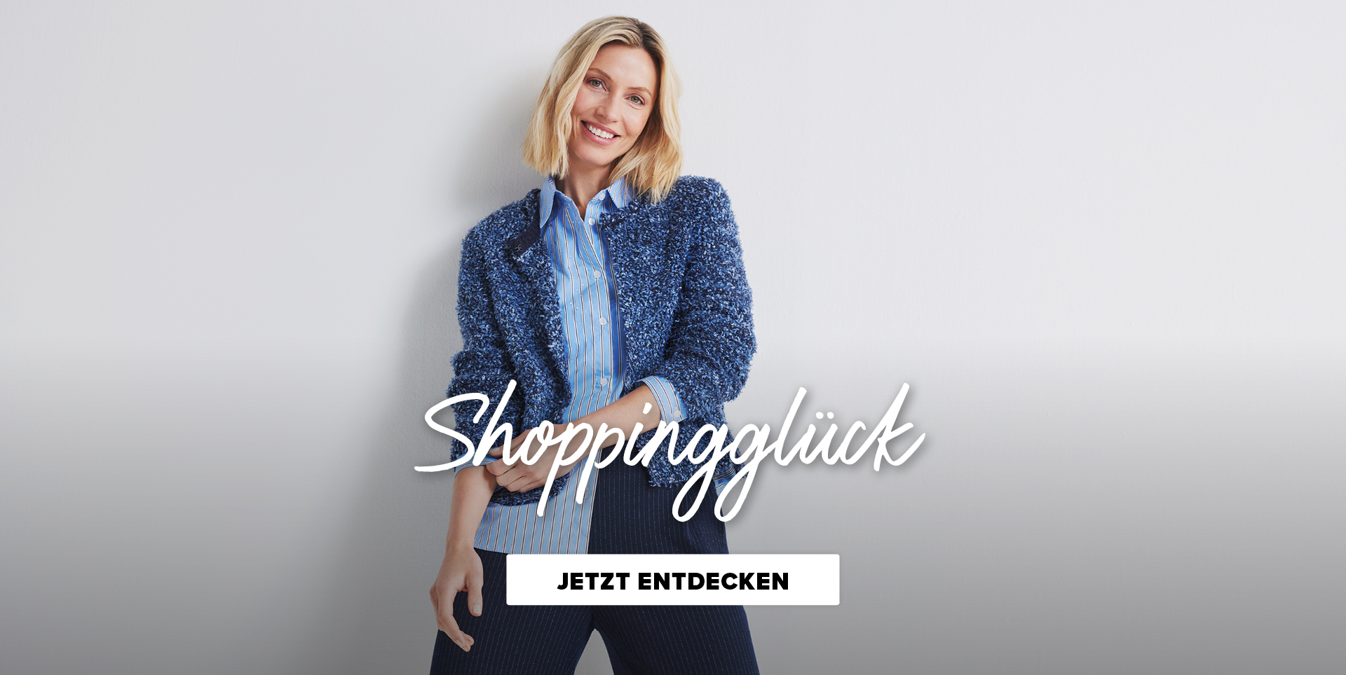 Eine lächelnde Frau trägt eine blåue Jacke und ein gestreiftes Hemd. Der Text "Shoppingglück" und "Jetzt entdecken" sind prominent dargestellt.