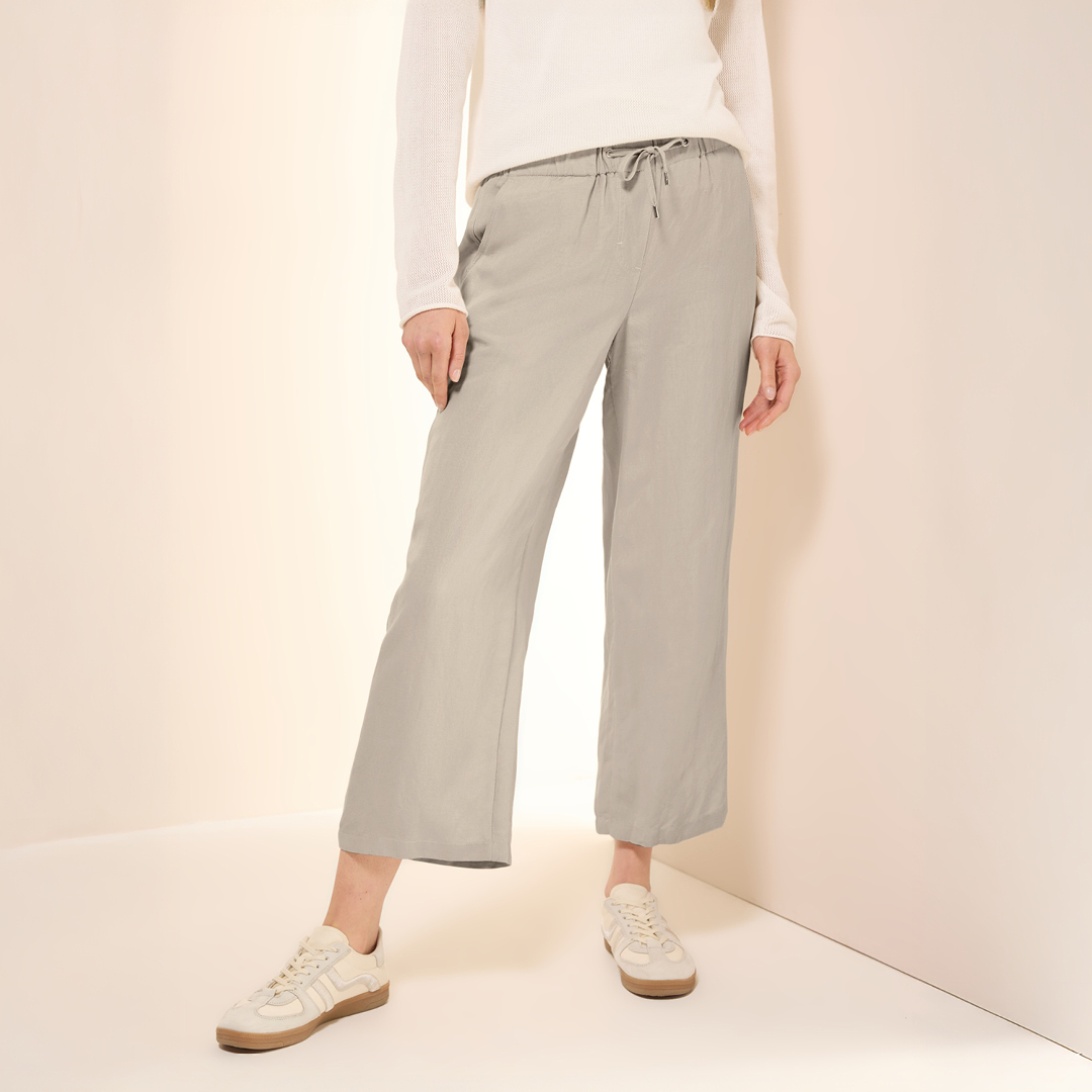 Eine Person trägt eine helle, bequeme Hose und Sneakers, stehend vor einem neutralen Hintergrund. Eine Person trägt eine helle, bequeme Hose und Sneakers, stehend vor einem neutralen Hintergrund.