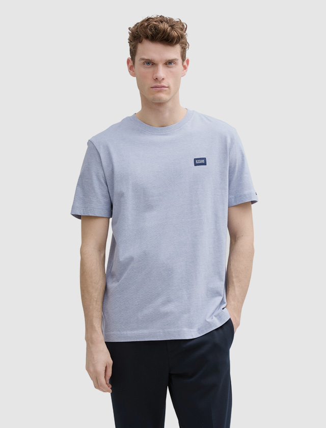 Ein Mann trägt ein hellblaues T-Shirt und steht vor einem neutralen Hintergrund. Ein Mann trägt ein hellblaues T-Shirt und steht vor einem neutralen Hintergrund.