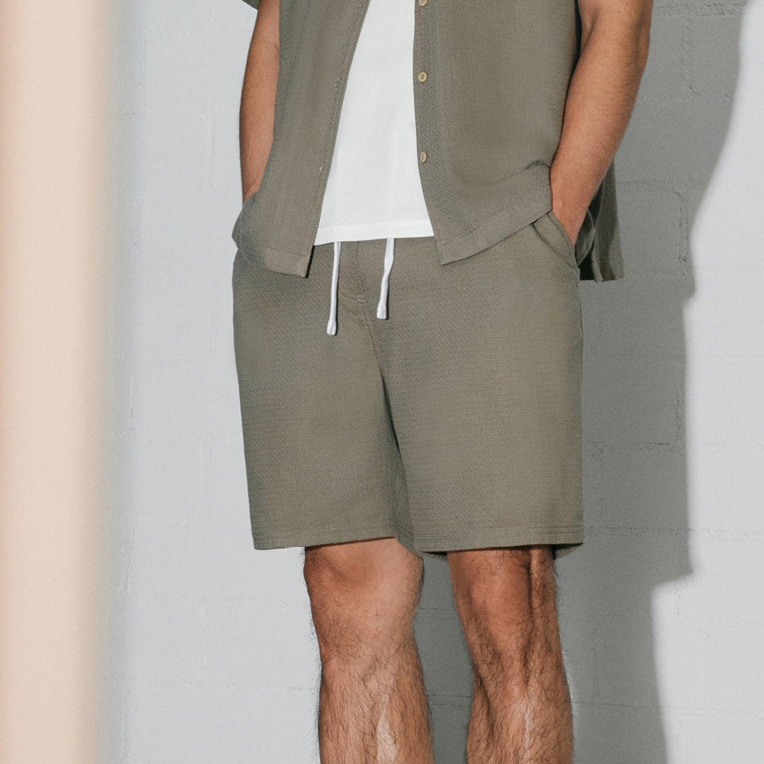Ein Mann trägt ein kurzärmliges Hemd und Shorts in Olivgrün. Ein Mann trägt ein kurzärmliges Hemd und Shorts in Olivgrün.